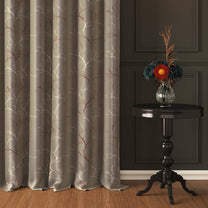 Two-piece blackout curtains with ivory and copper branch foil pattern, hanging beside a dark wooden table with a vase