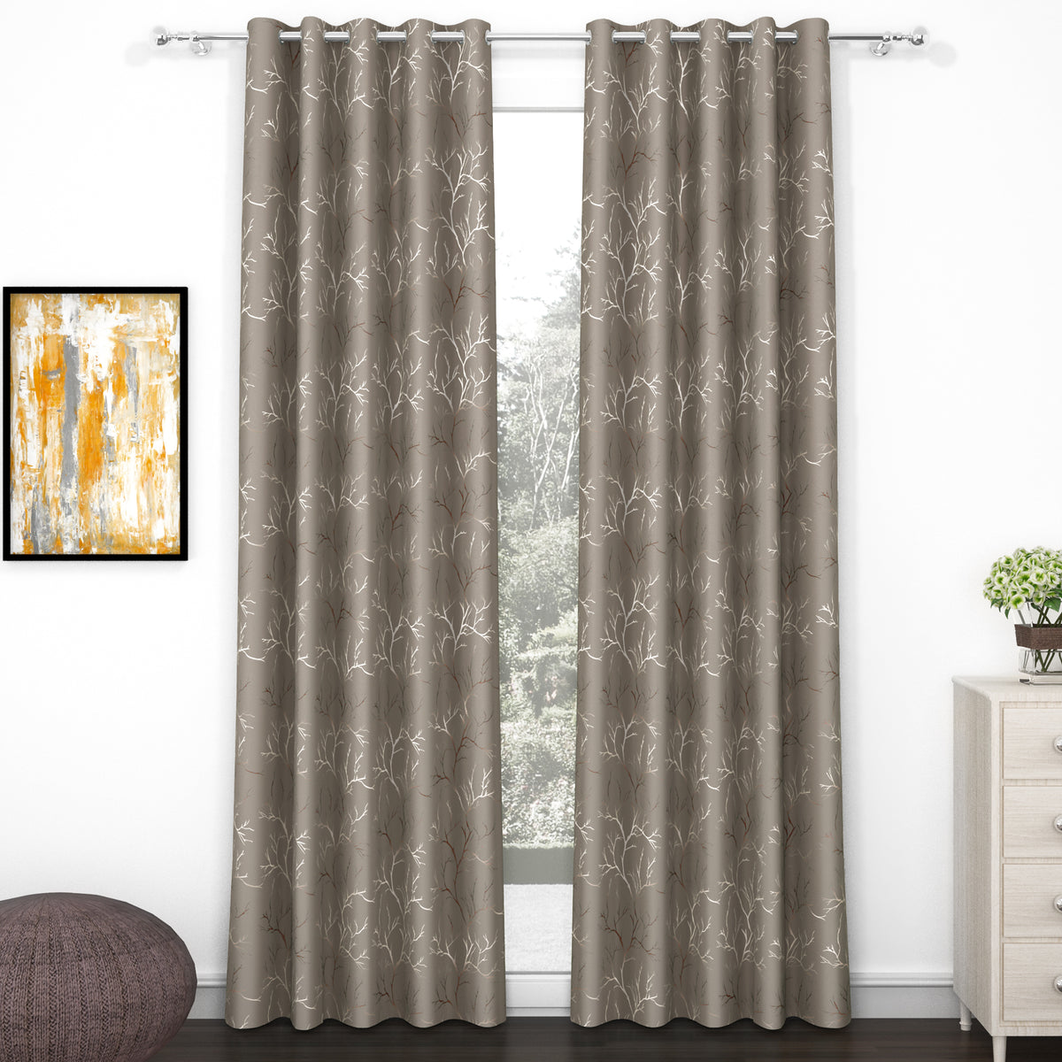 Two taupe blackout curtains with ivory and copper branch foil print, hanging on silver curtain rod in a room setting