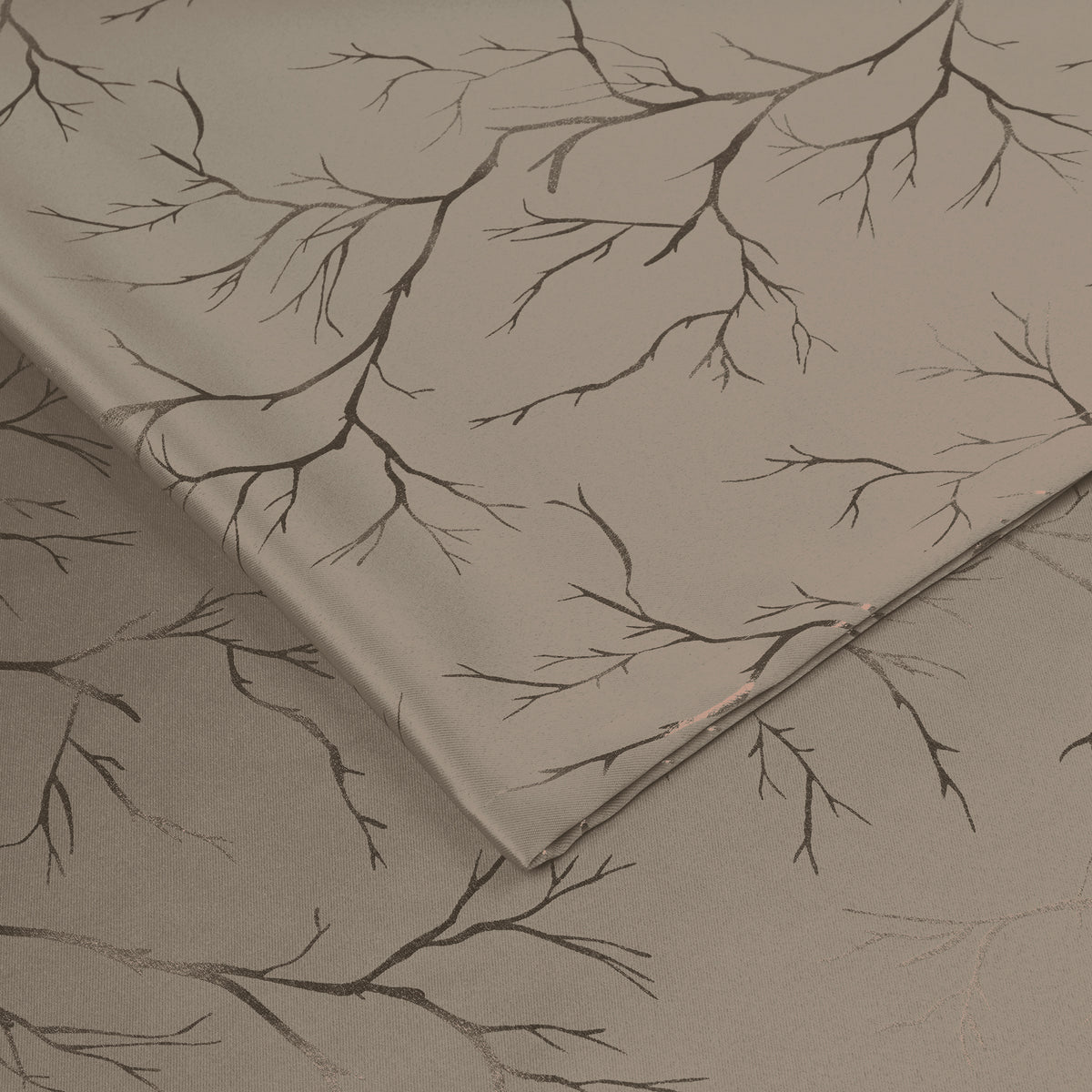Folded ivory blackout curtains with copper foil branch pattern, shown in close-up detail on fabric surface