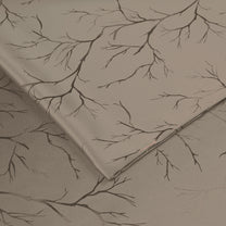 Folded ivory blackout curtains with copper foil branch pattern, shown in close-up detail on fabric surface