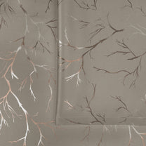 Ivory blackout curtain fabric with copper and silver foil branch pattern, shown folded and flat on surface