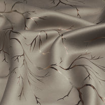 Ivory blackout curtain fabric with copper and bronze foil branch pattern, shown in a close-up folded view
