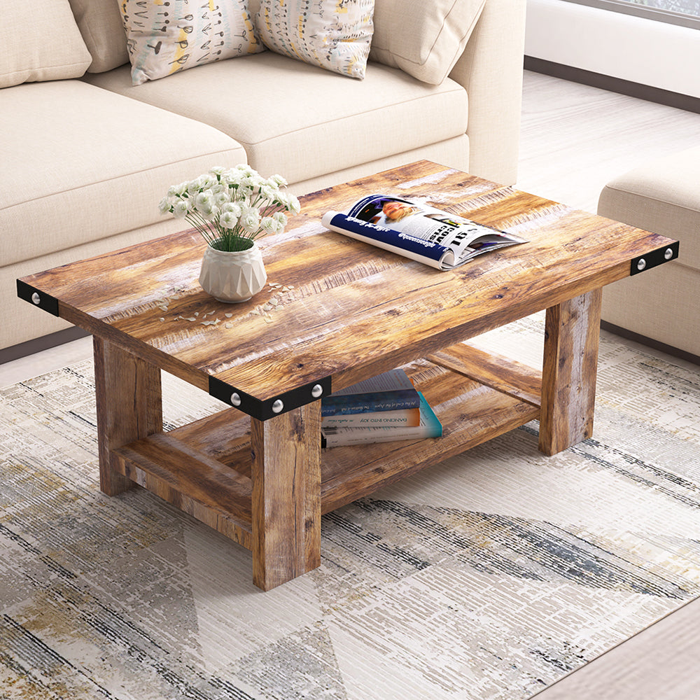 Wooden coffee table with metal accents in front of a beige sofa with patterned cushions.