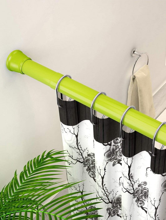 Close-up of a green curtain rod with black and white floral curtains and a plant beside it.